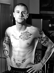 The heavily tattooed tough guy demurely stands on the scales covering his cock and balls